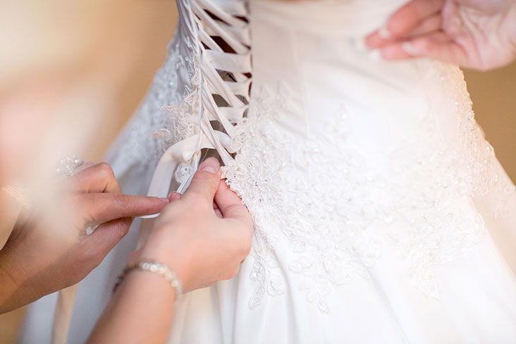 Buttoning up a wedding dress to wear on the big day. 