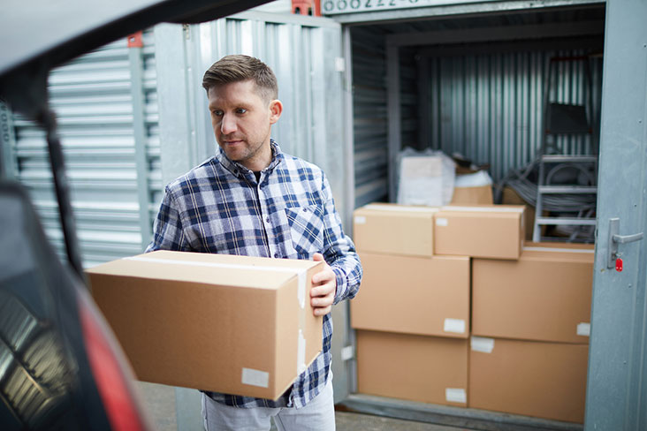 Young man packs a storage unit with belongings.